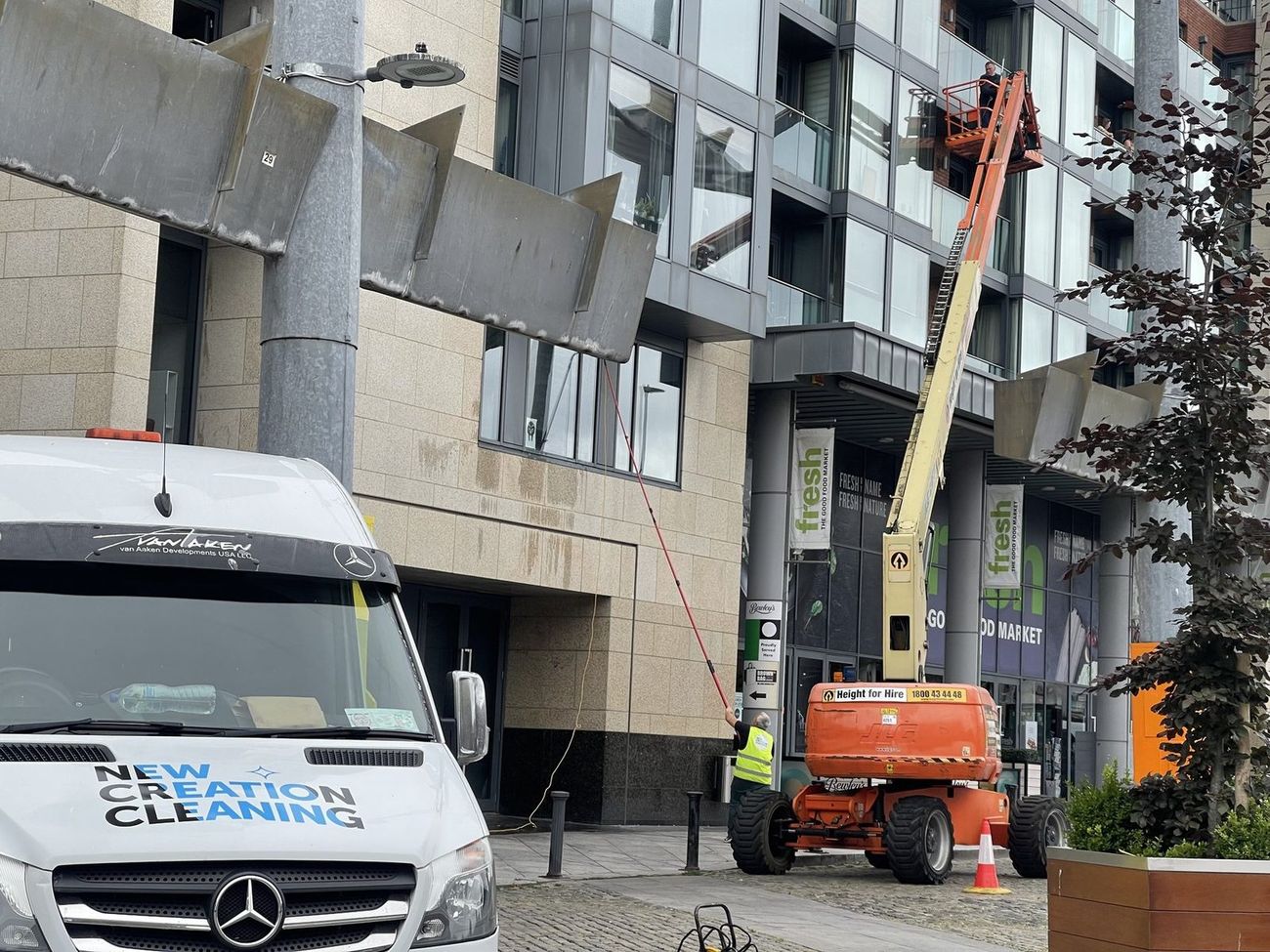 New Creation Cleaning crew using a boom lift and water-fed pole to clean a Dublin commercial building